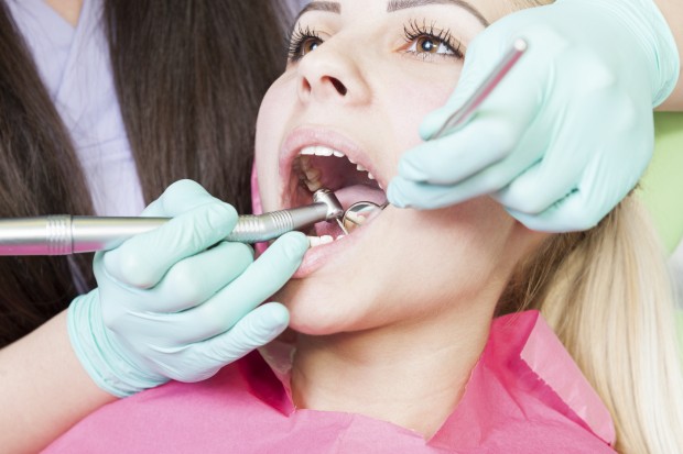 A professional dentist is operating on the inside of a patient's mouth in order to alleviate dentin hypersensitivity.