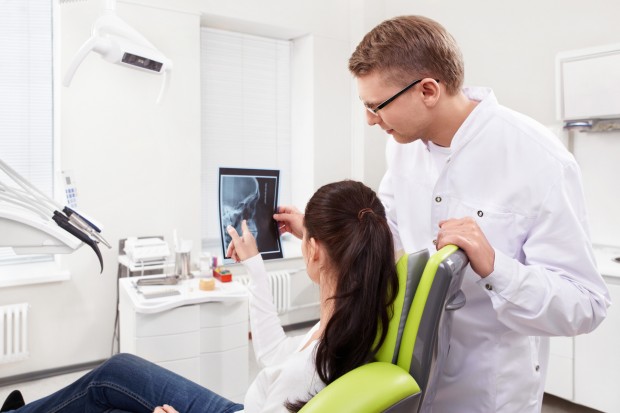A dentist is show a patient an x-ray and talking about the Nd: YAG.