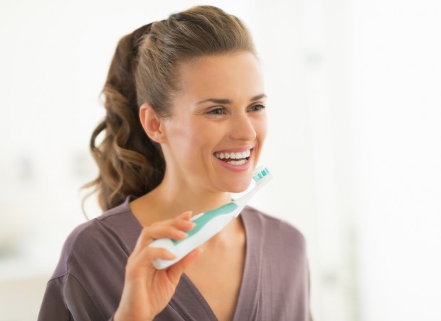 A happy young woman is about to demonstrate how to brush your teeth.