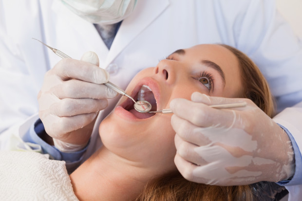 Dentist examining a patients teeth for periodontal disease.