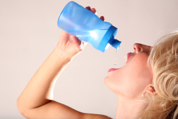 An attractive thirty-something female drinks water to combat xerostomia.
