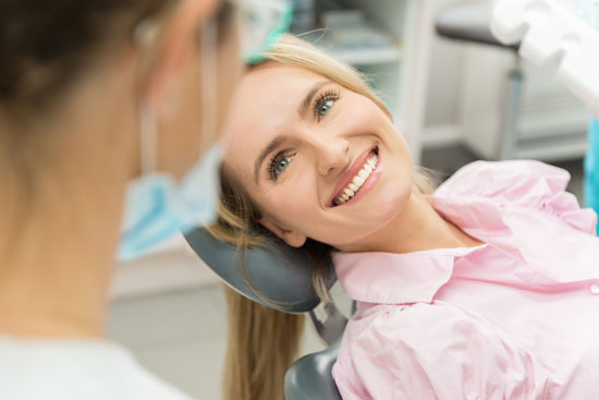A patient is smiling after receiving an examination of her gums. Regular examinations prevent gum disease later on.