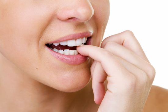 Nail-biting is observed in a woman with an attractive smile, which she is putting at risk.